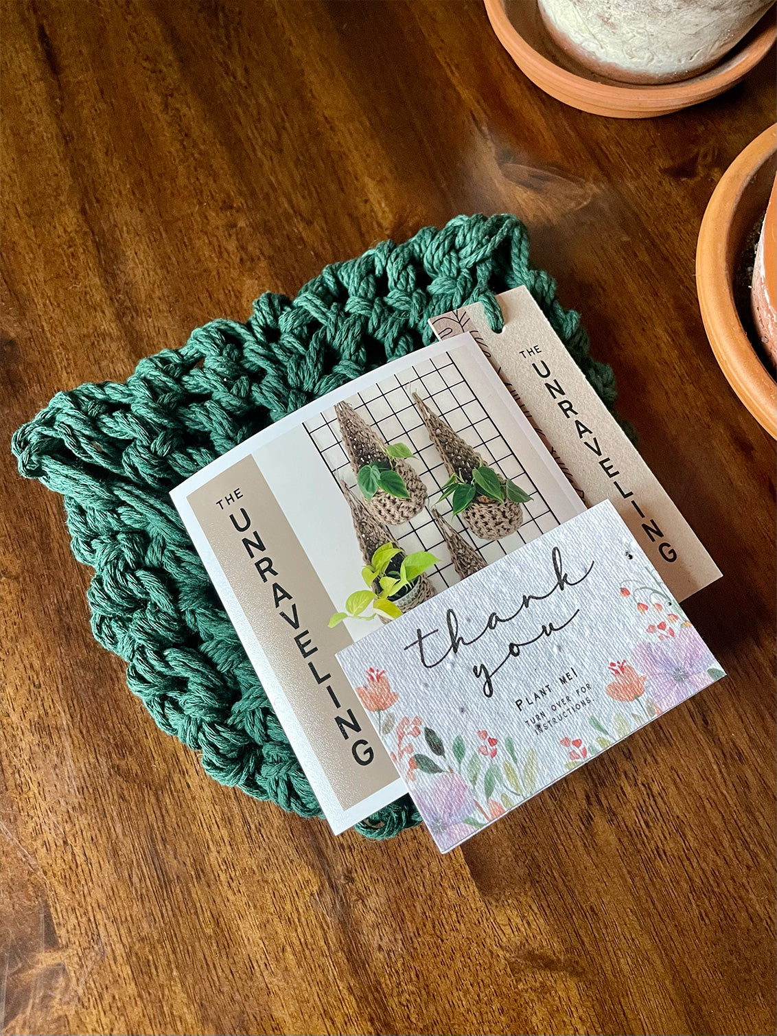 Photo showing handmade green plant hanger folded and ready for posting with handwritten note to the customer and thank you seed card.