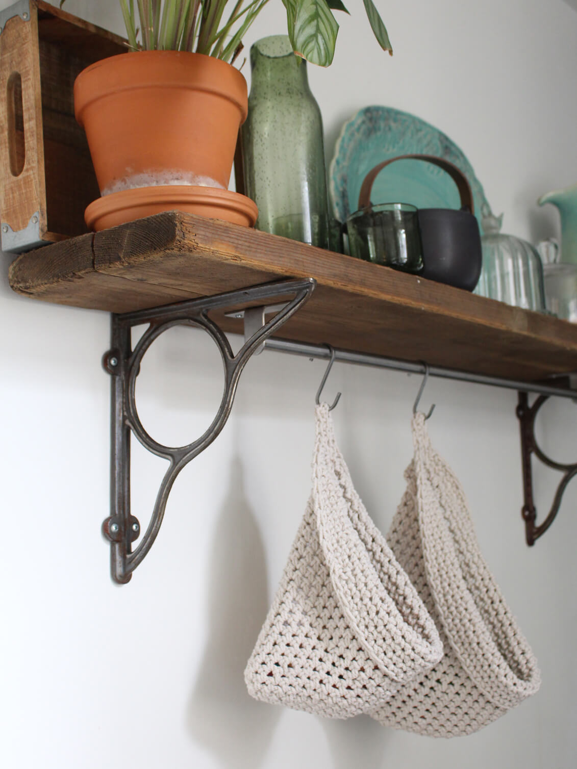 Photo showing white cotton small and large scandi storage bags in a kitchen suspended by metal hooks from a hanging shelf, the space saving storage bags are filled with fruits and vegetables