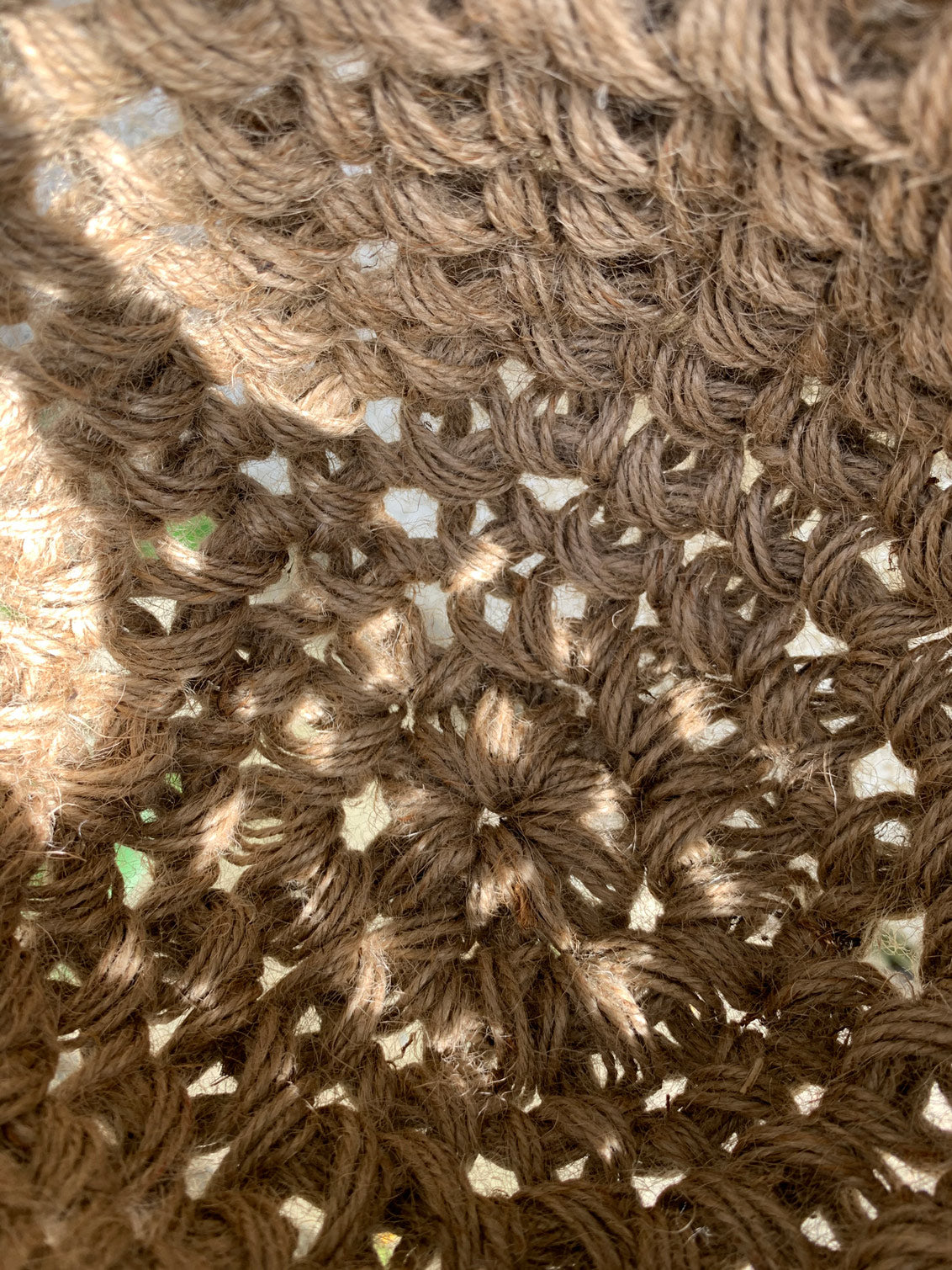 Close up photograph of the interior jute hanging basket, without pot or plant. Photo shows the pot like shape of the handmade crocheted basket and the woven texture of the fibres. Also shows how the basket is constructed, in the round.