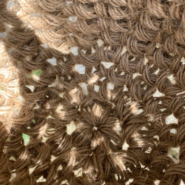 Close up photograph of the interior jute hanging basket, without pot or plant. Photo shows the pot like shape of the handmade crocheted basket and the woven texture of the fibres. Also shows how the basket is constructed, in the round.
