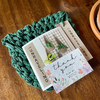 Photo showing handmade green plant hanger folded and ready for posting with handwritten note to the customer and thank you seed card.