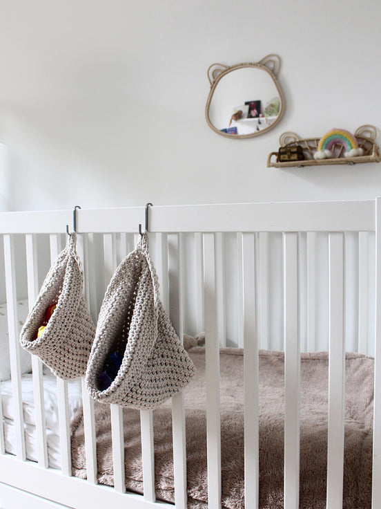  Photo showing white cotton small and large scandi storage bag in a childrens room hanging from the side of a bed from a small hook, storage bags are filled with childrens toys , space saving hanging room organiser