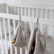  Photo showing white cotton small and large scandi storage bag in a childrens room hanging from the side of a bed from a small hook, storage bags are filled with childrens toys , space saving hanging room organiser