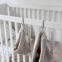  Photo showing white cotton small and large scandi storage bag in a childrens room hanging from the side of a bed from a small hook, storage bags are filled with childrens toys , space saving hanging room organiser