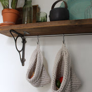 Photo showing white cotton small and large scandi storage bags in a kitchen suspended by metal hooks from a hanging shelf, the space saving storage bags are filled with fruits and vegetables
