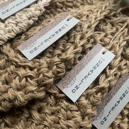 Photo showing 4 jute wall planters with swing tags, lying flat. Showing the tierdrop shape and The Unraveling branding. 